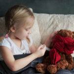 Ein Kind heilt seinen Teddybaer mit der richtigen Medizin gegen Fieber.