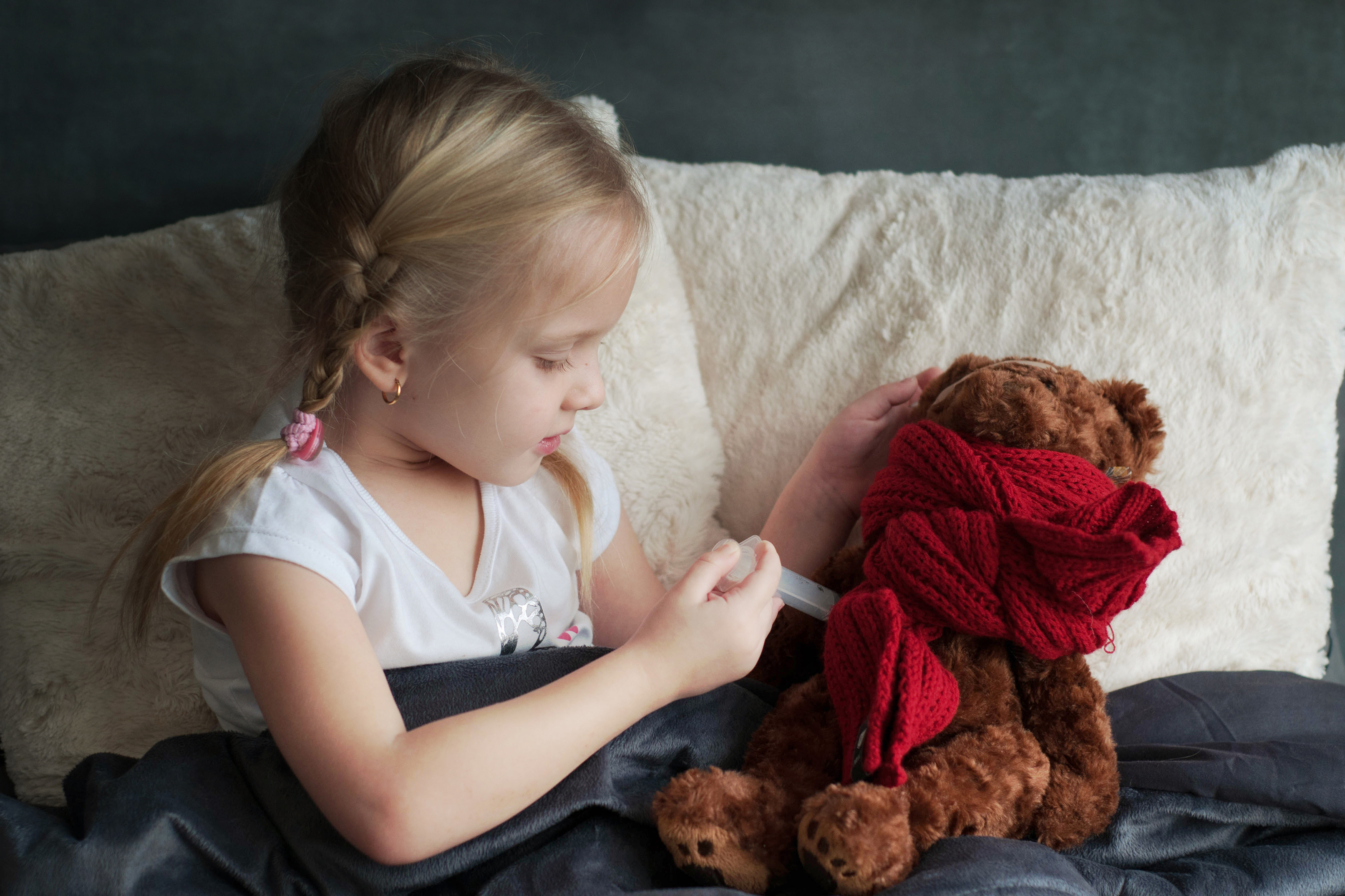 Ein Kind heilt seinen Teddybaer mit der richtigen Medizin gegen Fieber.