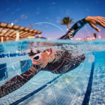 An athlete swimming in a pool wearing the cosinuss° One