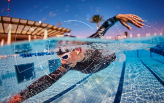 An athlete swimming in a pool wearing the cosinuss° One