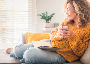 Eine frau relaxed zuhause mit einem Buch und einem Kaffee.