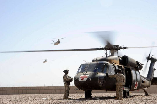 Ein medizinischer Verteidigungshubschrauber ist startbereit, während zwei Soldaten noch außen vor dem Hubschrauber stehen.