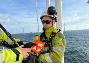 Die c-med Alpha Doppelladestation hält ein mann auf einer Windrad-Insel im Meer.
