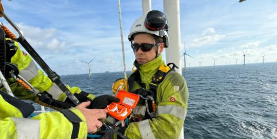Die c-med Alpha Doppelladestation hält ein mann auf einer Windrad-Insel im Meer.