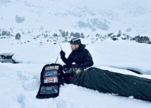 Michael Helbing funkt während einer Rettung im Schnee. Der Patient ist in Decken eingewickelt, um warm zu bleiben.