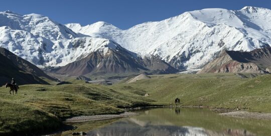 Lenin Peak Basecamp with snowy mountains in the background and a blue sky
